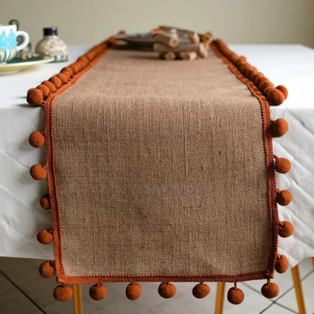 Jute-Tischläufer mit orangefarbenen Pompons